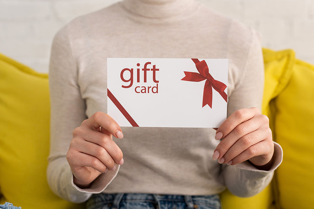 cropped-view-of-young-woman-showing-gift-card-2022-12-16-16-24-58-utc